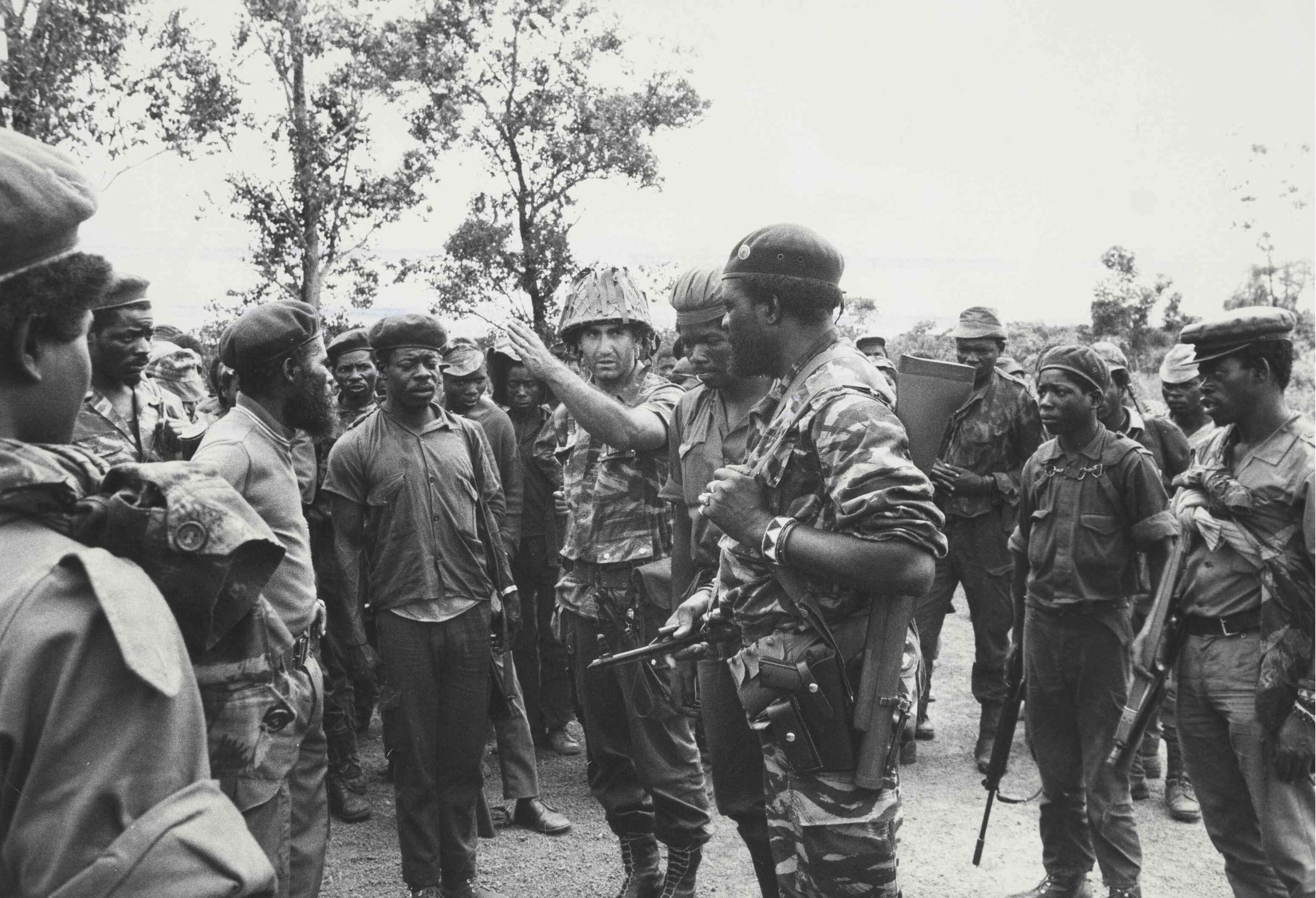 Jonas Savimbi, presidente da UNITA, ouvindo um oficial português no comando de uma unidade militar da UNITA a relatar a situação militar em Mussende, 26 de janeiro de 1976.Fotografia de Ingeborg Lippman. Fonte: FMSMB, Ingeborg Lippman