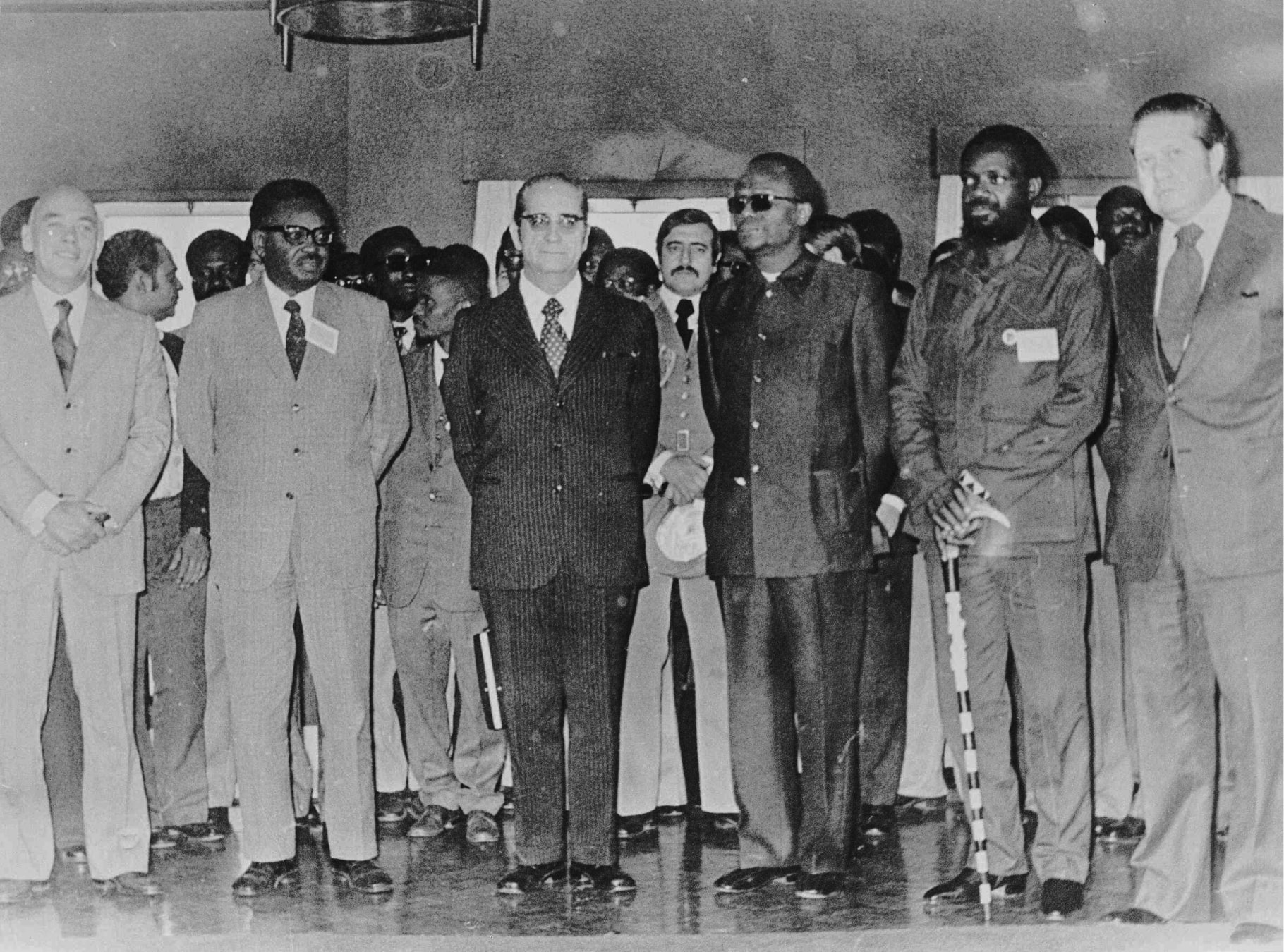 O almirante António Rosa Coutinho, Agostinho Neto (MPLA), general Francisco da Costa Gomes, Presidente da República, Holden Roberto (FNLA), Jonas Savimbi (UNITA) e Mário Soares, ministro dos Negócios Estrangeiros, no interior do hotel Penina (Alvor), durante as negociações entre Portugal e os movimentos de libertação angolanos, 10 de janeiro de 1975. Fotografia de Inácio Ludgero. Fonte: FMSMB