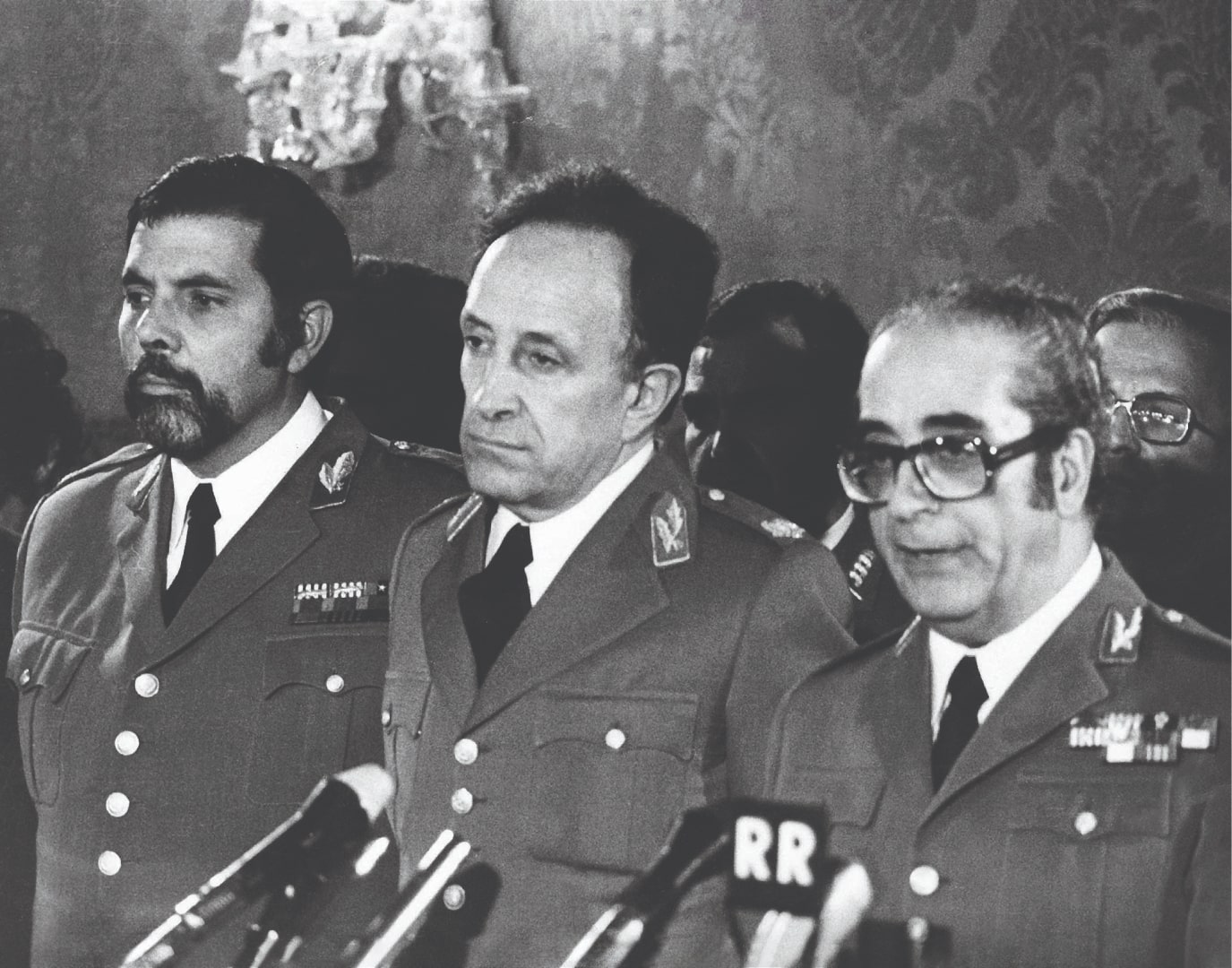 O Presidente da República, General Francisco da Costa Gomes, discursando na tomada de posse do Conselho da Revolução. A seu lado, Vasco Gonçalves (Primeiro-Ministro) e Carlos Fabião (Chefe do Estado-Maior do Exército). Lisboa, 17 de março de 1975. Fotografia de Carlos Gil. ANTT, Coleção Flama.