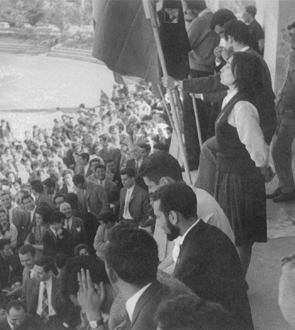 Isabel do Carmo, em primeiro plano, a falar num plenário no Estádio Universitário. A sua intervenção foi destacada pela PIDE num relatório. 1962. Fonte: Coleção particular de Isabel do Carmo.